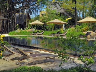 Poklidný bazén s lehátky a slunečníky v bujné zahradě