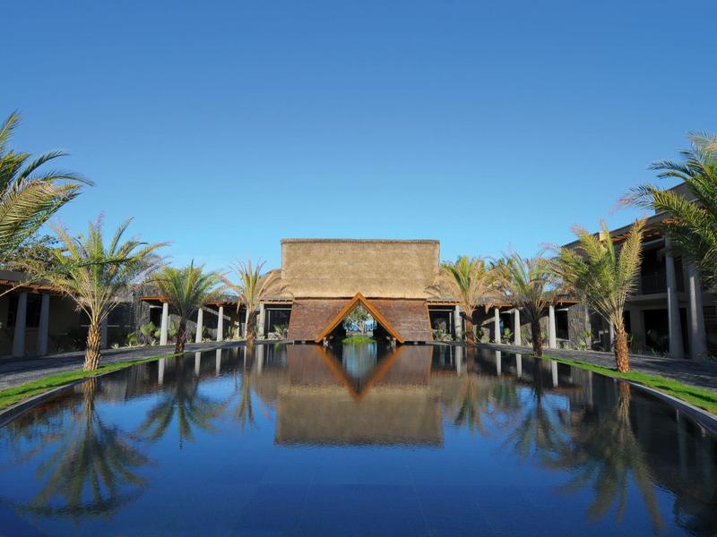 Moderní hotelový komplex s velkou vodní nádrží a dvěma řadami palem a budov.