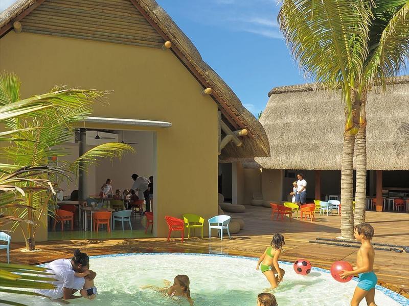 Děti si hrají v malém bazénu vedle tropického domu s palmovou zahradou.