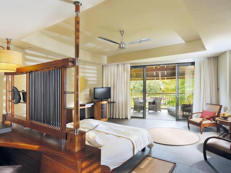 Světý hotelový pokoj s velkou postelí, televizí a přístupem na terasu s výhledem na zahradu.