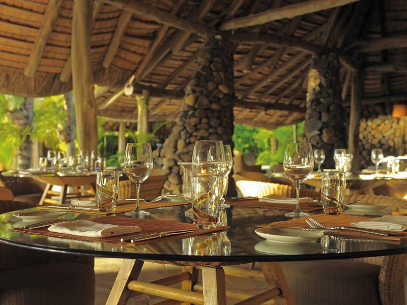 Offenes Restaurant mit Holzdach, runden Glastischen und geschmückten gedeckten Plätzen.