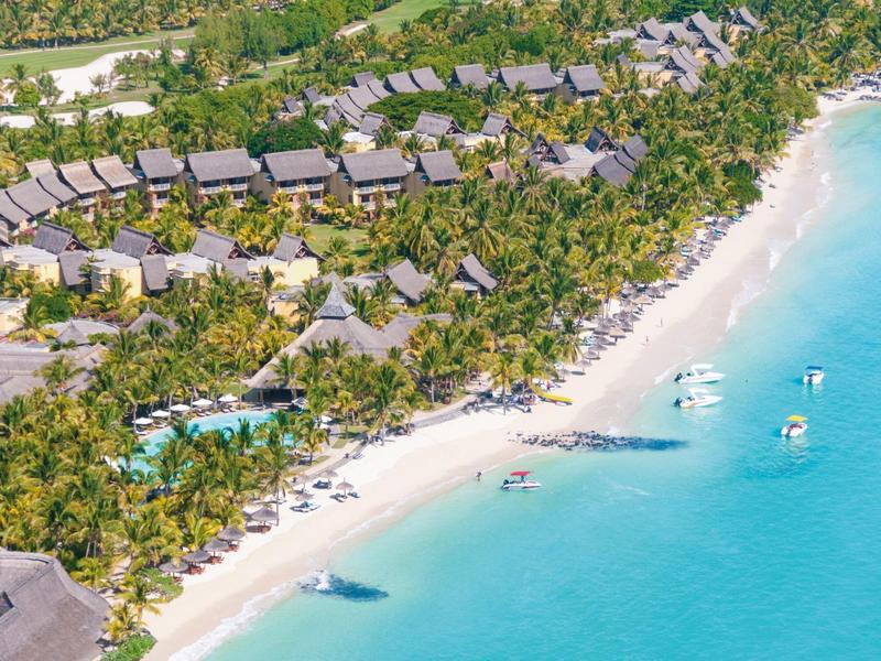 Luftaufnahme von Strandresort mit Palmen, weißen Stränden, blauer Lagune und Bungalows am Ufer.
