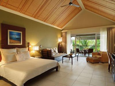 Großes, helles Schlafzimmer mit Holzbalkendecke, Doppelbett, Sitzbereich und weitem Fensterblick.