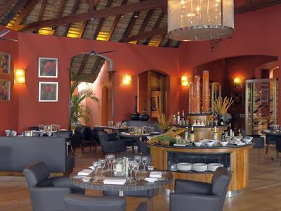 Elegantní restaurace s dřevěným stropem, moderním nábytkem a teplým osvětlením.