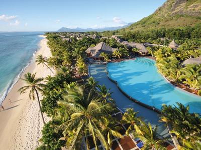 Přímořské letovisko s velkým bazénem, palmami a horou v pozadí.