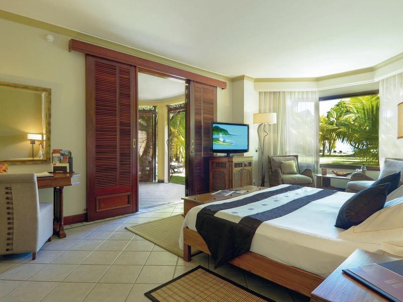 Moderně zařízený hotelový pokoj s otevřeným přístupem na terasu a výhledem do zahrady.