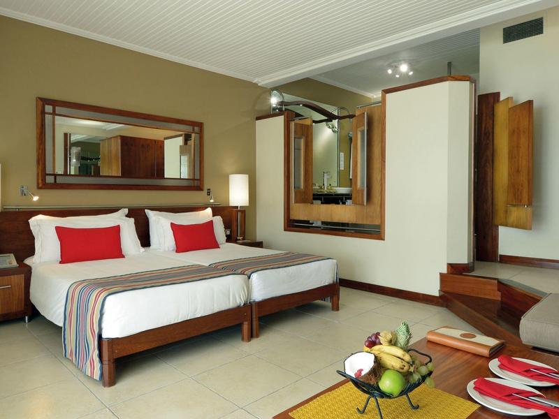 Modern eingerichtetes Hotelzimmer mit zwei Einzelbetten, Spiegeln und gedecktem Tisch.