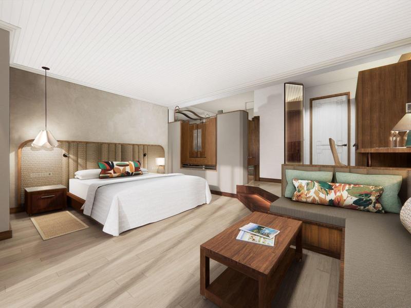 Modernes Schlafzimmer mit großem Bett, Holzmöbeln und gemütlicher Sitzecke in warmen Beige- und Brauntönen.