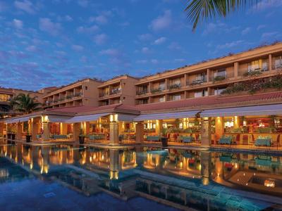 Ein Hotel mit beleuchteten Zimmern und einem Pool bei Sonnenuntergang.