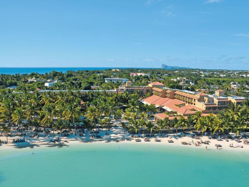 Beach resort with palm trees, white sand, and clear turquoise water by the sea.