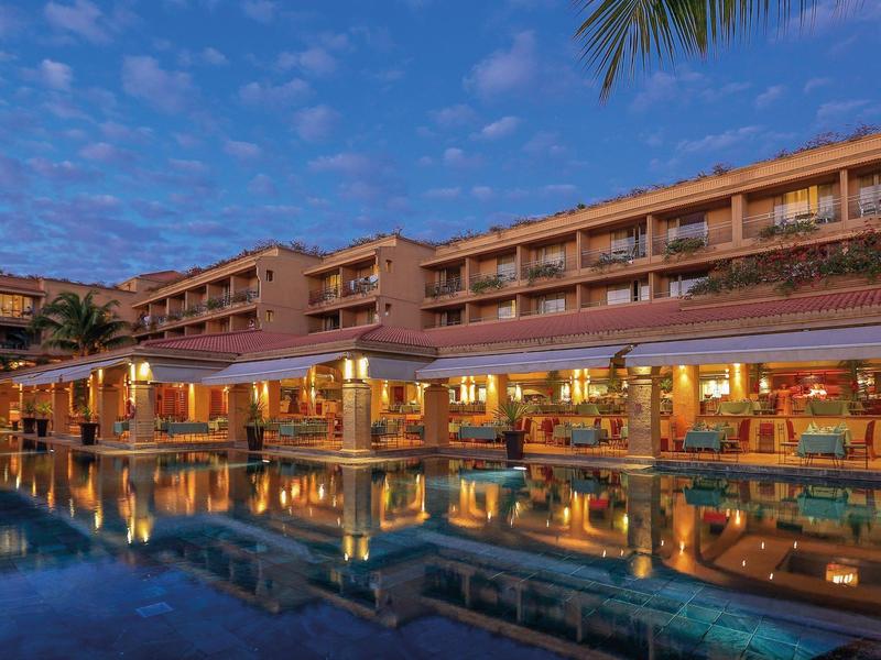 Hotel complex with illuminated pool at sunset and clear sky.