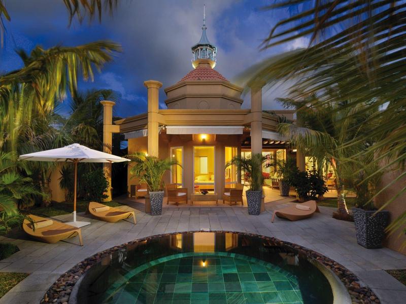 Luxurious villa with lighting, round pool, and tropical plants at dusk