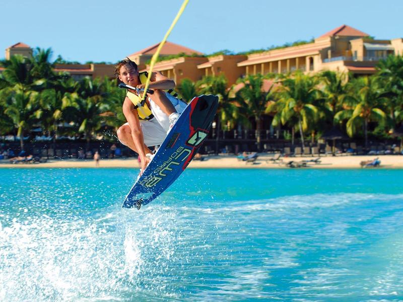 Person wakeboarding in front of tropical hotel beach