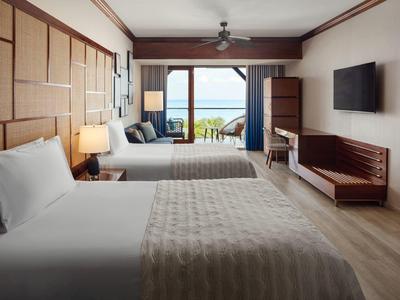 Modernes Hotelzimmer mit zwei Doppelbetten, Meerblick und elegantem Holzdekor.