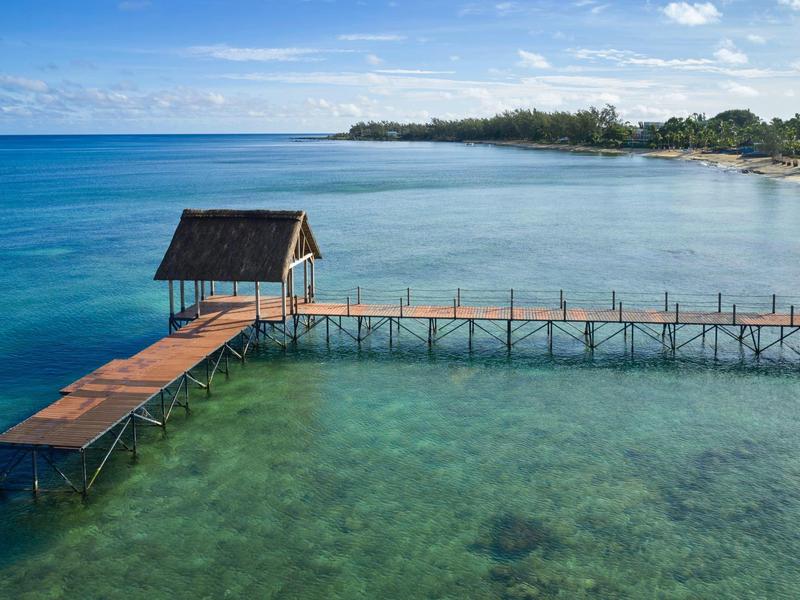 Houten pier met klein hutje boven helder zeewater en kustlijn op de achtergrond