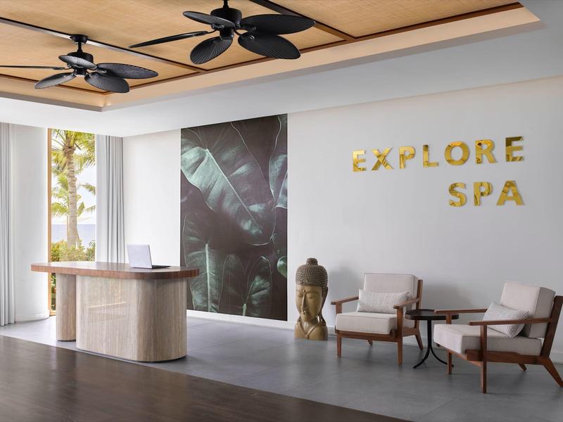 Moderne spa-receptieruimte met houten balie, zitplaatsen en gouden letters aan de muur.