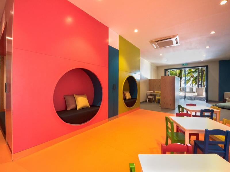 Kleurrijke speelruimte in een hotel met zitniches in de muur en kindermeubilair.