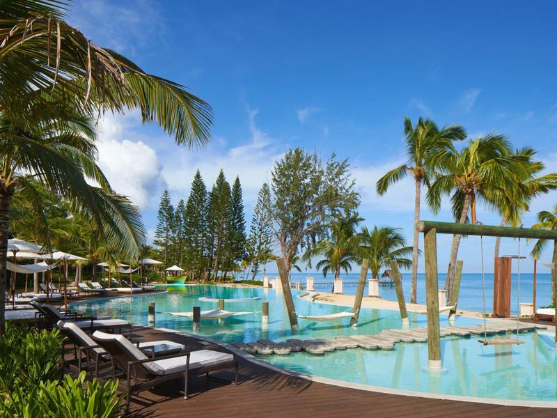 Luxe zwembad met ligstoelen en palmbomen onder een blauwe lucht