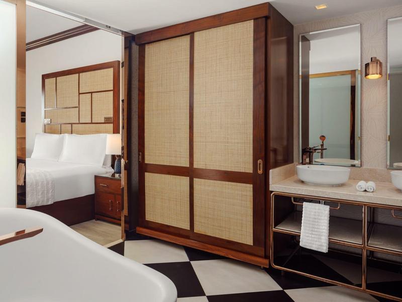 Moderne hotelkamer met badkuip, kast en wastafels met spiegels in warm licht