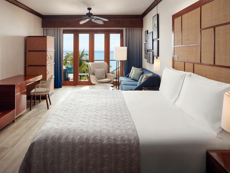 Modern hotelkamer met groot bed, terras en uitzicht op zee.