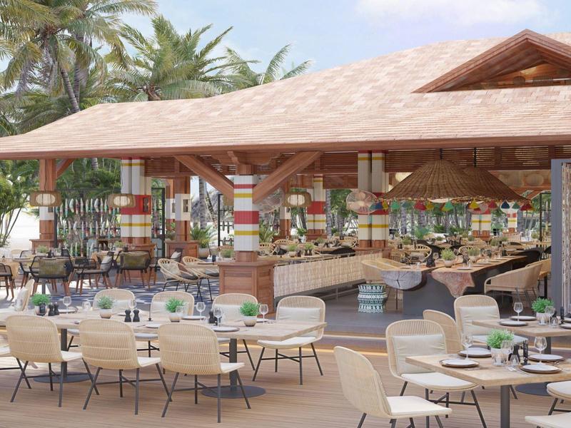 Buitenrestaurant met moderne stoelen en tafels onder een groot paviljoen in een tropische omgeving.