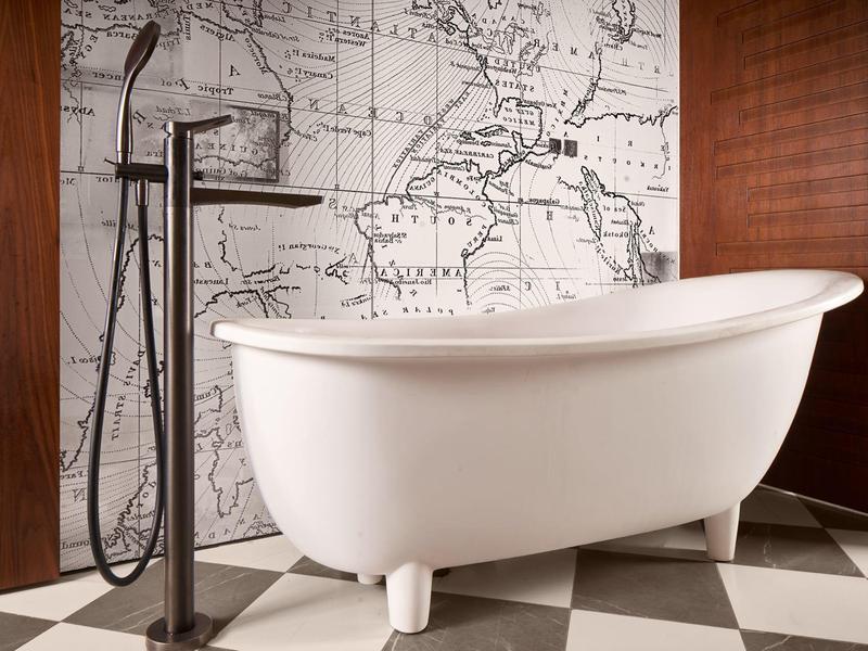 Witte vrijstaande badkuip voor een wereldkaartmuur, zwart-witte vloer en houten wanden