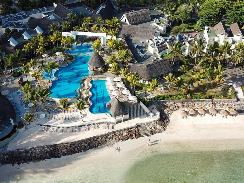 Strandresort mit großen blauen Pools, Palmen und weißen Sandstränden am klaren Meer.