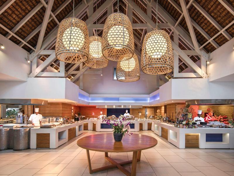 Moderner Buffetbereich mit Holzdecke, runden Lampen und rundem Holztisch mit Blumenarrangement.