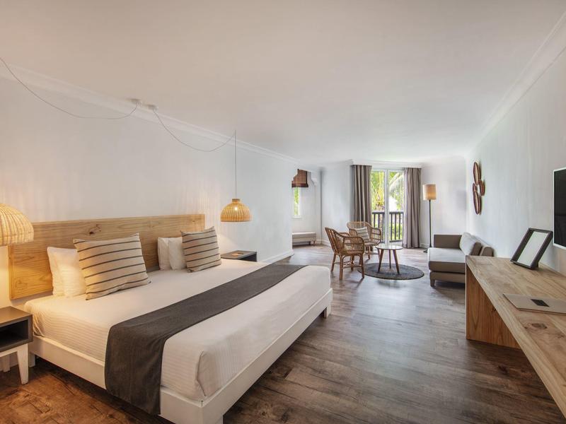 Helles, modernes Hotelzimmer mit Doppelbett, Holzmöbeln und großem Fenster mit Blick nach draußen.