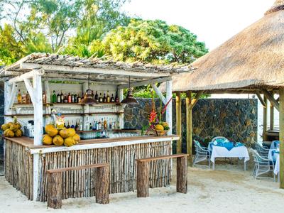 Offene Strandbar aus Holz mit Getränken und Strohüberdachung im tropischen Ambiente.