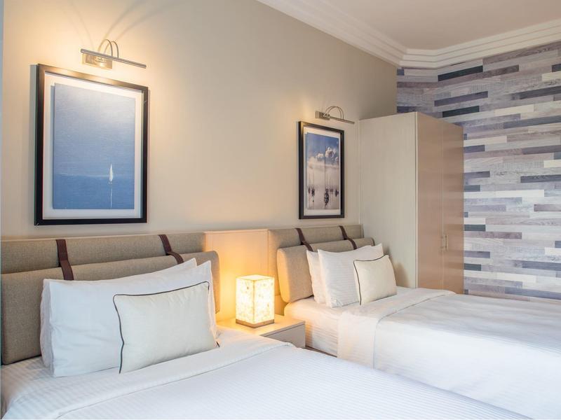 Modernly furnished bedroom with two double beds, nightstand, and stylish wall decoration.