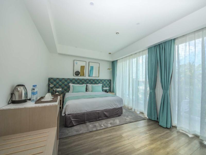 Moderne slaapkamer met groot bed, grijs hoofdeinde en vloerlange ramen met gordijnen.