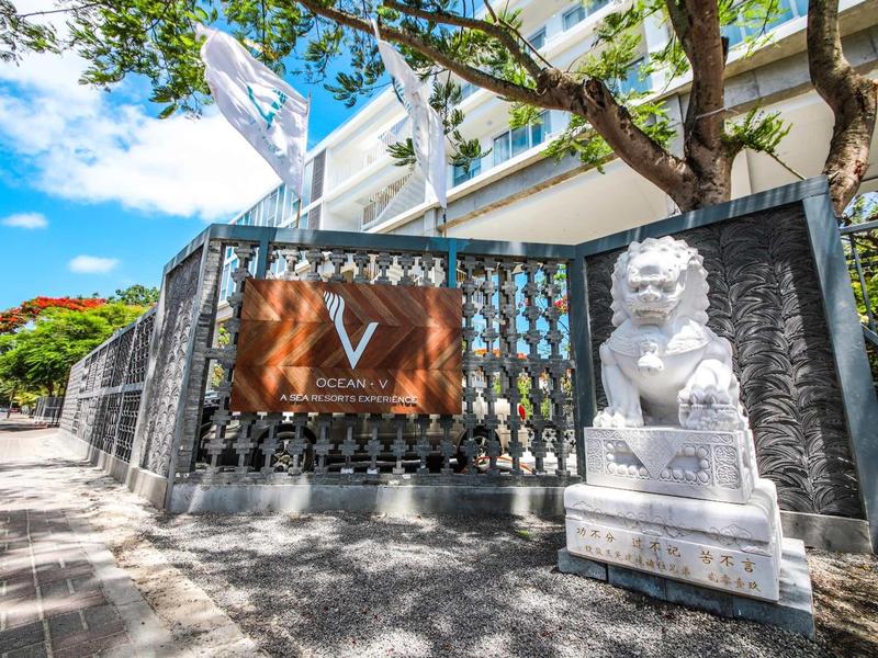 Buitenkant van een hotel met een leeuwenbeeld en decoratief hek bij zonnig weer.