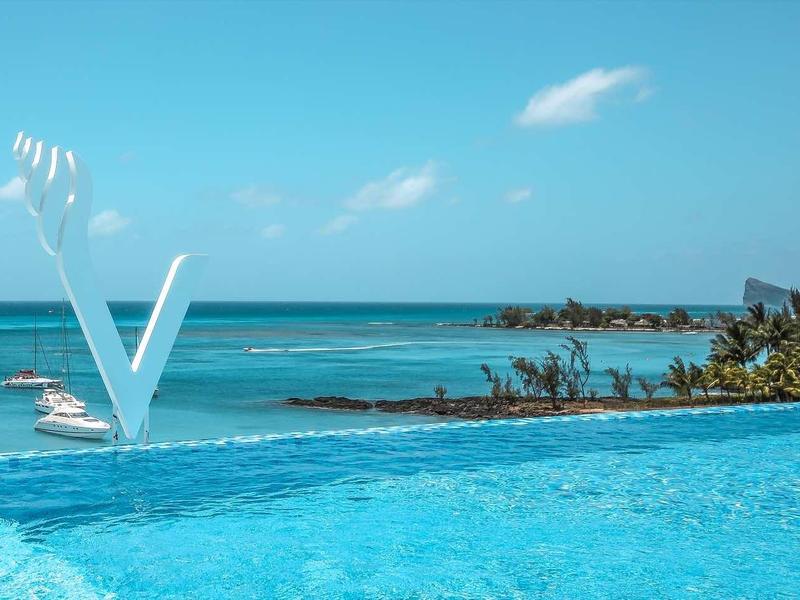 Infinity-zwembad met helderblauw water en uitzicht op zee bij zonnige hemel.