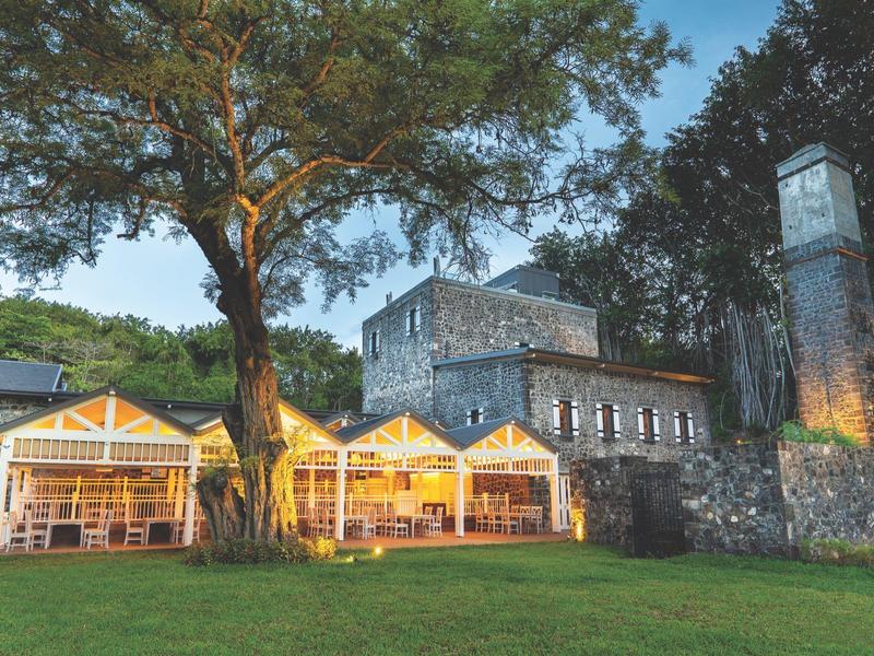 Verlichte paviljoens voor een oude stenen vesting met bomen bij schemering.