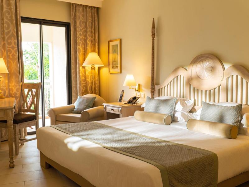 Lichte hotelkamer met een comfortabel tweepersoonsbed, zithoek en toegang tot het terras.