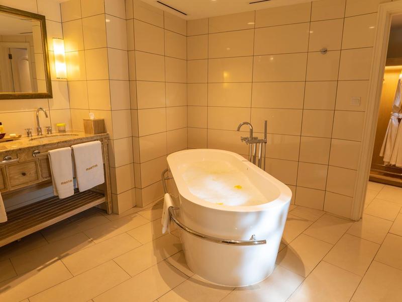 Modern hotelbadkamer met vrijstaand bad en grote spiegel.