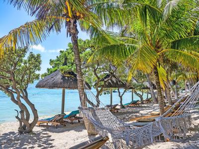 Strand mit Hängematten unter Palmen und Strohdächern am ruhigen Meer
