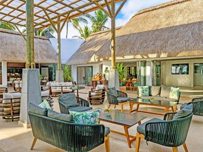 Gemütlicher Außenbereich mit modernen Sitzmöbeln und überdachten Strohdächern im Resort.