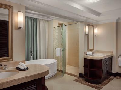 Moderne hotelbadkamer met vrijstaand bad, glazen douche en dubbele wastafel.