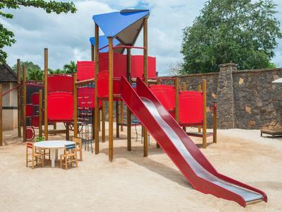 Speelplaats met rode glijbaan en zandige ondergrond buiten.