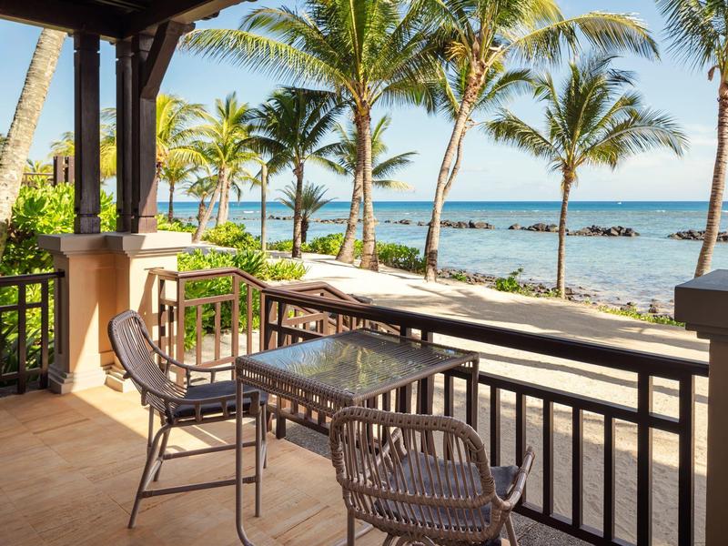 Balkon met tafel en stoelen met uitzicht op palmbomen en helder oceaanwater