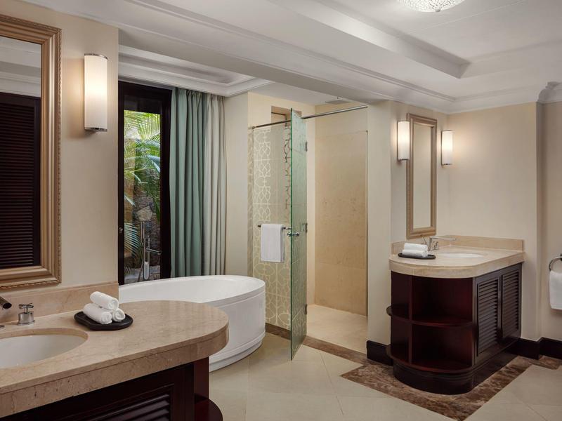 Elegante badkamer met vrijstaand bad, glazen douche en dubbele wastafel.