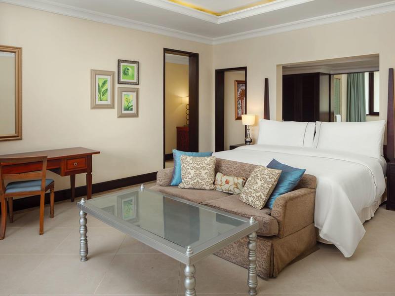 Modern hotelkamer met groot bed, bank en bureau.