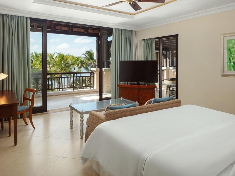 Lichte hotelkamer met grote ramen, balkon en zeezicht.