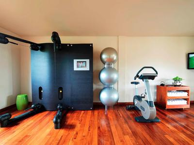 Moderner Fitnessraum mit Heimtrainer, Gymnastikbällen und Holzboden in einem Hotelzimmer.