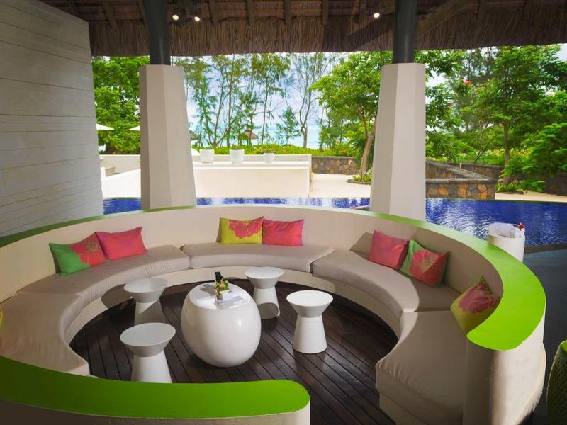 Nowoczesna, okrągła strefa wypoczynkowa z kolorowymi poduszkami na tropikalnym zewnątrz przy basenie.