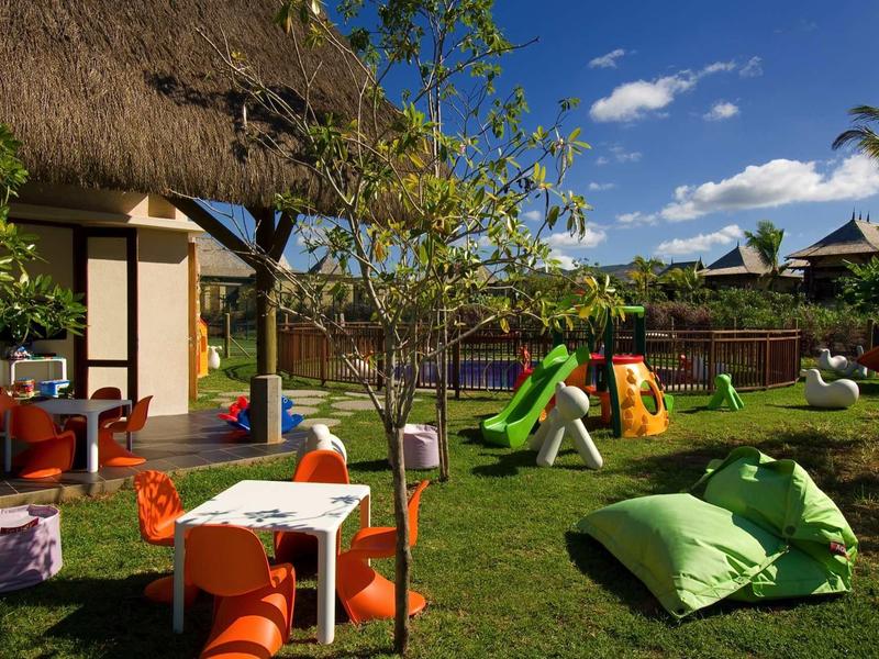 Kolorowy plac zabaw dla dzieci ze zjeżdżalniami i miejscami do siedzenia w hotelowym ogrodzie w słoneczny dzień.