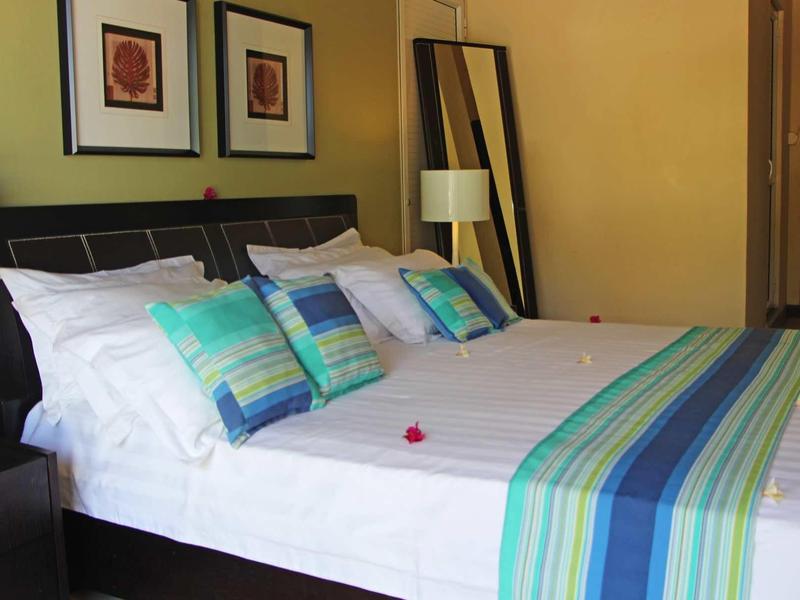 Chambre d'hôtel confortable avec grand lit, coussins colorés et lampes modernes.