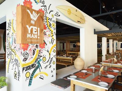 Modernes Restaurant mit hölzernen Tischen, Stühlen und bunter Wanddekoration.